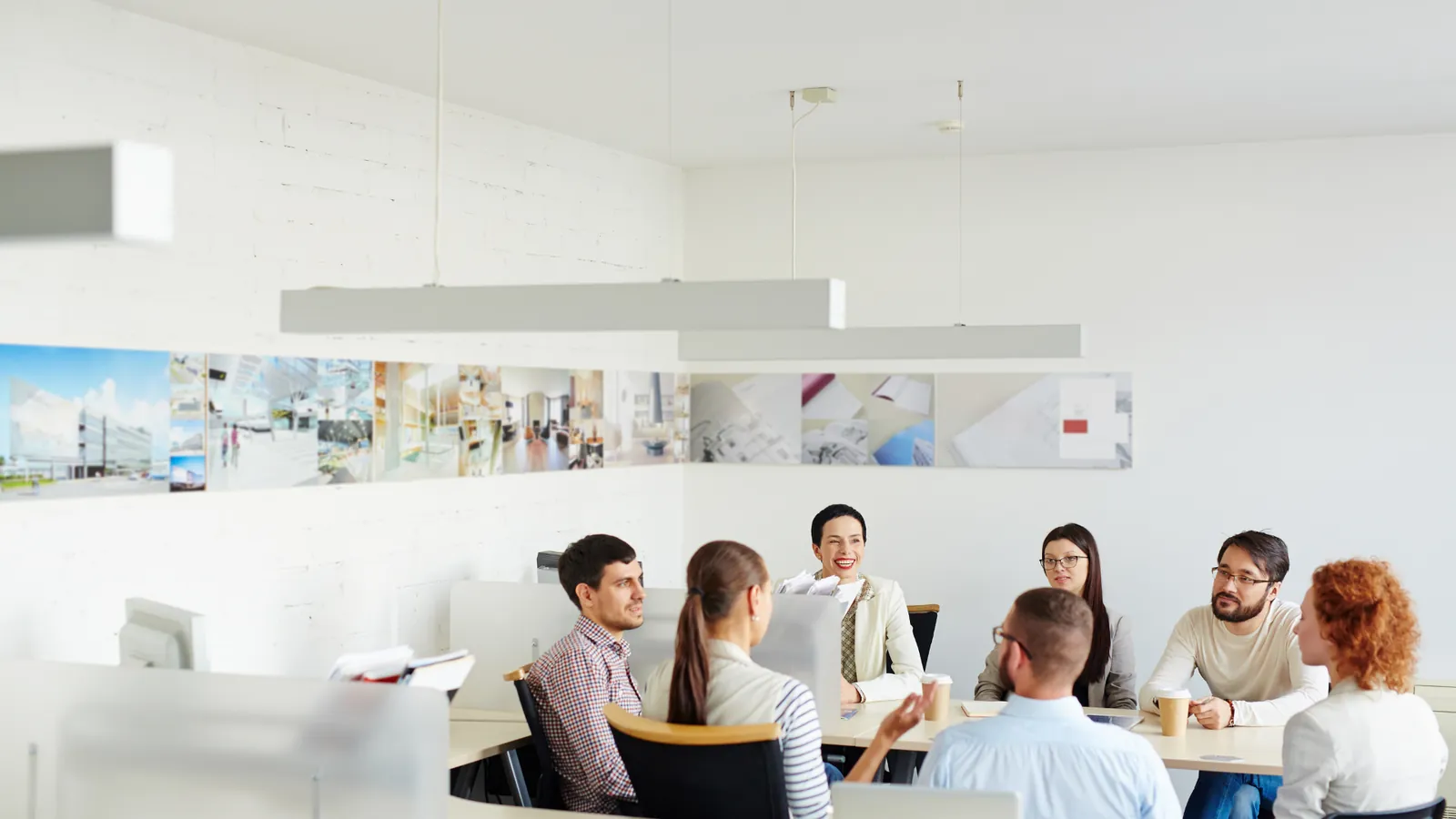 Colleagues seated around a table in a bright open-plan office.