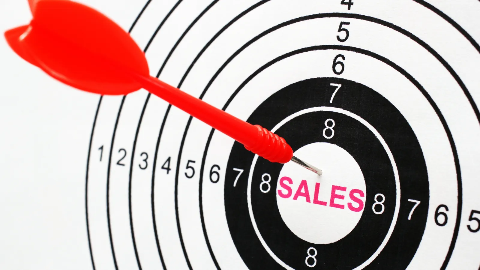 A dart in the centre of a target marked "sales".