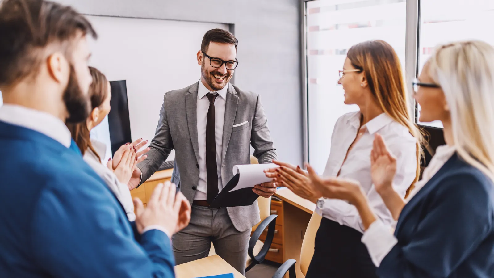 A small team applauding a colleague at the end of a meeting.